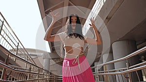 Slow motion. Low Angle Shot. An attractive girl with long hair energetically dances a street dance with elements of
