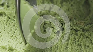 Slow motion macro of pistachio ice cream being scooped with spoon