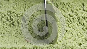 Slow motion macro of pistachio ice cream being scooped with spoon