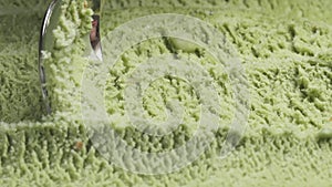 Slow motion macro of pistachio ice cream being scooped with spoon