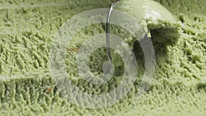 Slow motion macro of pistachio ice cream being scooped with spoon