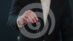 Slow motion of male`s midsection in formal jacket holding house keys in hand and showing to camera. Real-estate agent