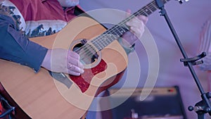 Slow motion: man hands playing acoustic guitar on stage of open air concert