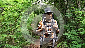 Slow-motion of man traveler with backpack walking and looking in natural forest