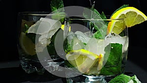slow motion Mojito refreshing cocktail pouring, alcohol drink. Lemonade with lemon and mint leaves on dark background