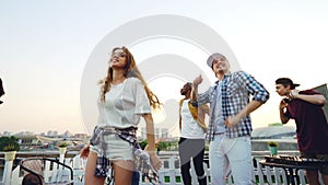 Slow motion of multi-ethnic group of friends dancing and relaxing at open-air party with DJ using professional equipment