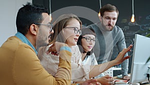 Slow motion of multi-ethnic group of people talking in office pointing at computer screen