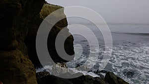 Slow motion: Pacific Ocean waves move toward rocky outcropping, lighthouse point