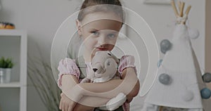 Slow motion portrait of adorable child standing at home hugging stuffed toy smiling looking at camera