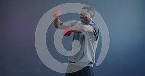 Slow motion portrait of African American guy boxing concentrated on shadow fight on purple color background