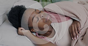 Slow motion portrait of African American lady sleeping then waking up in bed in the morning