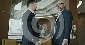 Slow motion portrait of business partners shaking hands and talking in modern hotel