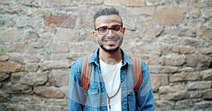 Slow motion portrait of charismatic Arabian man smiling outdoors near brick wall