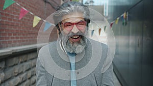 Slow motion portrait of cheerful man in stylish sun glasses laughing outside against urban background