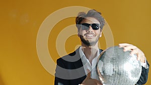 Slow motion portrait of cheerful mixed race man holding glitterball and dancing