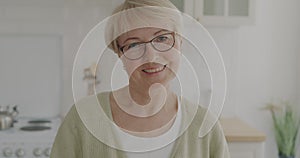 Slow motion portrait of cheerful senior lady weaaring eyeglasses smiling looking at camera at home