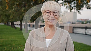 Slow motion portrait of elegant elderly woman smiling standing outdoors in urban street