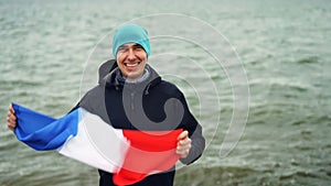 Slow motion portrait of excited Frenchman cheerful patriot holding French flag and moving hands celebrating freedom and