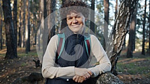 Slow motion portrait of female hiker with backpack smiling looking at camera in forest