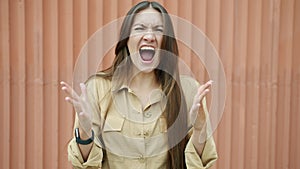 Slow motion portrait of furious young woman screaming expressing rage and aggression outdoors