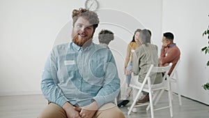 Slow motion portrait of handsome guy smiling feeling relief during support group meeting in psychological center