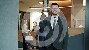 Slow motion portrait of handsome middle-aged businessman in suit standing in hotel lobby