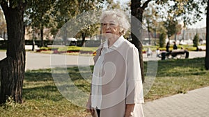 Slow motion portrait of happy elderly woman walking outdoors in city street looking around smiling