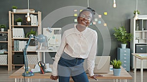 Slow motion portrait of happy mixed race girl wearing glasses standing in office alone smiling