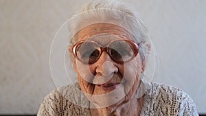 Slow motion portrait of a happy senior woman with gray hair and glasses.