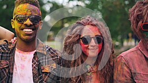Slow motion portrait of happy young men and women with dirty faces and clothing looking at camera wearing sunglasses and