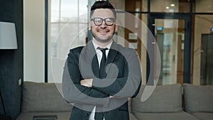 Slow motion portrait of joyful businessman in formalwear and glasses standing in lobby
