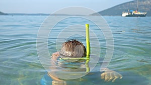 Slow motion portrait of little boy wearing diving mask and breathing tube submerging underwater at the sea