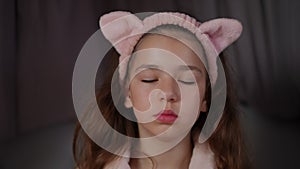 Slow motion. Portrait of a little girl who closed her eyes and meditates. A pretty girl with long hair and a pink