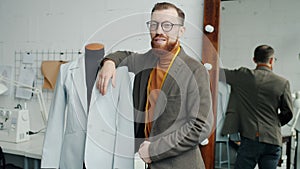 Slow motion portrait of male fashion designer standing in studio near dummy wearing new handsmade garment