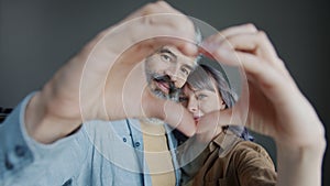 Slow motion portrait of man and woman smiling looking at camera making heart shape with hands