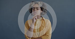 Slow motion portrait of young African American woman thinking then raising finger having great idea on gray background