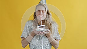 Slow motion portrait of young woman blowing candle on birthday cake making wish