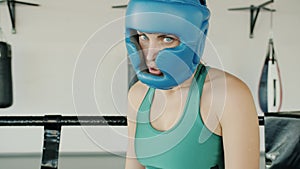 Slow motion portrait of young woman wearing safety helmet standing in ring resting