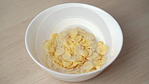 Slow motion of pouring corn flakes in a white plate close up.