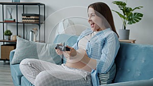 Slow motion of pregnant woman playing video game smiling having fun alone at home