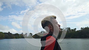 Slow motion profile shot of a young man running beside lake
