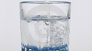 Slow motion. Pure water pouring into a glass mug on white background.