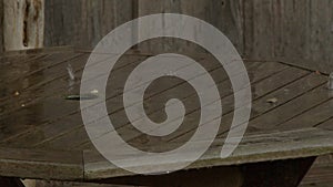 slow motion of rain pattering on wooden table in garden