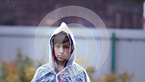 Slow Motion Rainy Day: Boy in Raincoat Looks at Camera