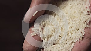 Slow motion raw rice grains falling from man`s hand