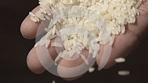 Slow motion raw rice grains falling from man`s hand