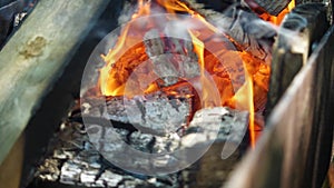 In slow motion the red embers and bright flames in the brazier. Close-up of the wood burning in the fire. Reverse