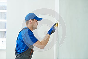 Refurbishment. Worker spackling a wall with putty photo