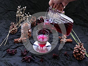 Slow motion : Roselle tea Jamaica sorrel, Rozelle or hibiscus sabdariffa  is poured from a kettle into glass cup with dry rosell