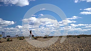 Slow motion of running slim young girl to seaguls and try frighten off them. Nice cloudy blue sky